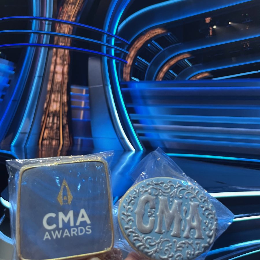 A printed CMA Awards logo cookie next to a hand-piped CMA cookie with silver scrollwork
